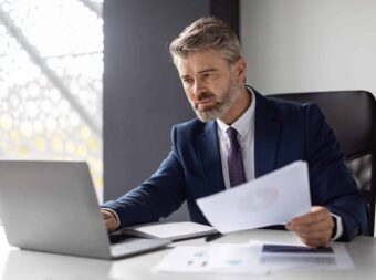 Busy Mature Businessman Working With Laptop And Documents In Office