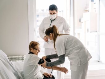 Doctors diagnosing blood pressure of senior woman